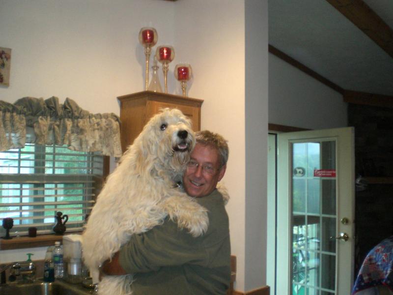 Man holding his large white goldendoodle in his kitchen