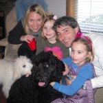 White and black goldendoodle with family of 4